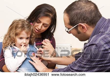 Stock Image - "GP doctor's surgery, patient consultation with a young girl receiving a bravery sticker, United Kingdom, Europe". Fotosearch