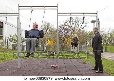 "Grandfather and his granddaughter, 3 years, playing on swings, grandmother standing next to them" View Large Photo Image Stock Photo - "Grandfather and his granddaughter, 3 years, playing on swings, grandmother standing next to them". Fotosearch