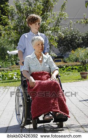 "Grandson is pushing his grandmother in a wheelchair, outdoors" View Large Photo Image Stock Image - "Grandson is pushing his grandmother in a wheelchair, outdoors". Fotosearch