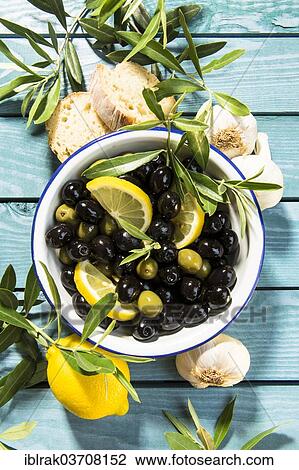 "Green and black olives in a bowl with olive branches, bread and lemons, Germany, Europe" View Large Photo Image Stock Image - "Green and black olives in a bowl with olive branches, bread and lemons, Germany, Europe". Fotosearch