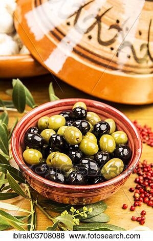 Stock Photo - "Green and black olives in a bowl with olive branches and peppercorns, Germany, Europe". Fotosearch