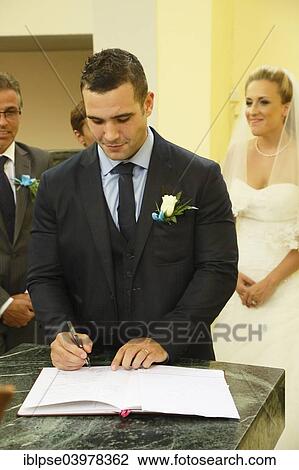 Stock Image - Groom signing the church register after the ceremony. Fotosearch
