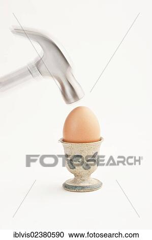 Stock Image - Hammer about to hit a brown egg. Fotosearch