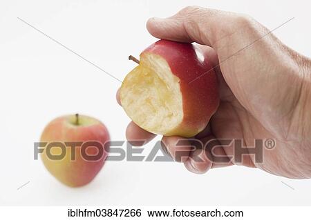 Stock Photograph - Hand holding a half eaten apple. Fotosearch