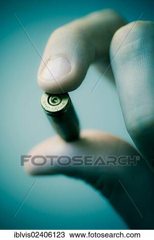 Stock Image - Hand holding bullet. Fotosearch