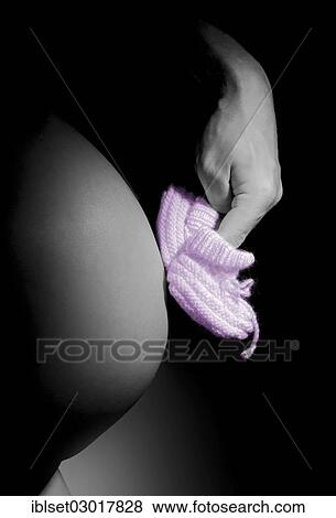 Stock Photo - Hand making pink baby shoes walk on a pregnant belly. Fotosearch