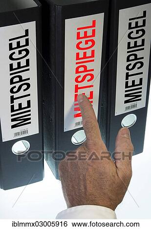 Stock Photograph - "Hand pointing to a file folder labeled """"Mietspiegel"""", German for """"rent index""""". Fotosearch