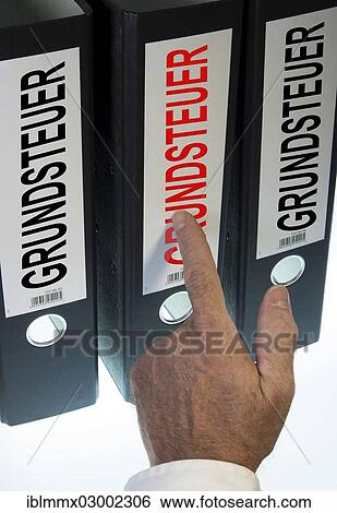 Stock Photograph - "Hand pointing to file folders labeled """"Grundsteuer"""", German for """"land tax""""". Fotosearch