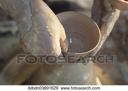 Hands molding a piece of pottery on a wheel head View Large Photo Image Stock Photo - Hands molding a piece of pottery on a wheel head. Fotosearch
