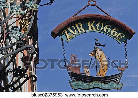 Stock Image - "Hanging sign of the """"Zur Kogge"""" restaurant in the old town of Stralsund, Mecklenburg-Western Pomerania, Germany, Europe". Fotosearch