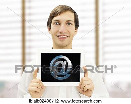 Stock Image - "Happy businessman, holding an iPad with an at symbol". Fotosearch