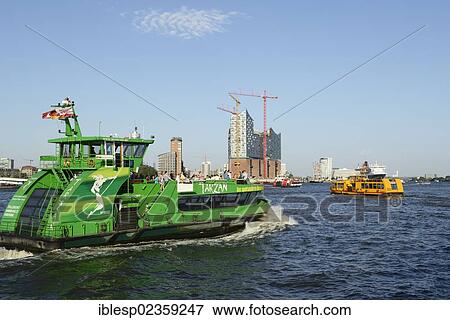 Stock Photo - "Harbour ferry on the Elbe river, RMS Queen Mary 2 at back, visiting during Hamburg Cruise Days, Port of Hamburg with the Elbe Philharmonic Hall under construction, Hamburg, Hamburg, Germany, Europe". Fotosearch