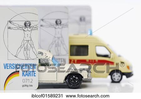 Stock Image - "Health insurance cards and miniature ambulances, symbolic image for financial difficulties of health insurances". Fotosearch