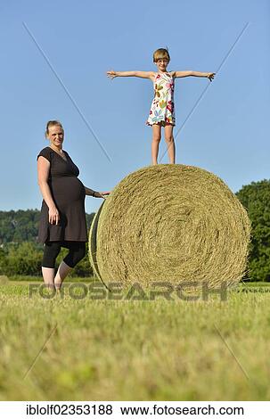 "Heavily pregnant women, nine months, and girl, six years, standing on a straw bale, Germany, Europe" View Large Photo Image Stock Photo - "Heavily pregnant women, nine months, and girl, six years, standing on a straw bale, Germany, Europe". Fotosearch
