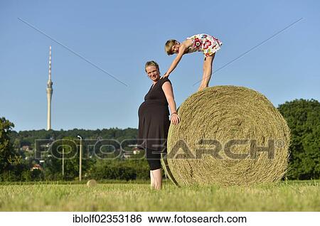 "Heavily pregnant women, nine months, and girl, six years, standing on a straw bale, Germany, Europe" View Large Photo Image Stock Photograph - "Heavily pregnant women, nine months, and girl, six years, standing on a straw bale, Germany, Europe". Fotosearch