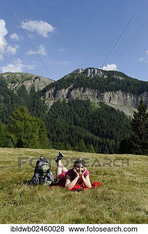 Stock Photo - "Hiker lying on the Raschoetz alp, Col de Raiser mountain at the back, near St. Ulrich, Val Gardena valley, Province of Bolzano-Bozen, Alto Adige, Italy, Europe". Fotosearch