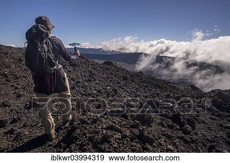 Stock Photo - "Hiker on the Piton de la Fournaise volcano with views of the Piton des Neiges volcano, Reunion, Africa". Fotosearch