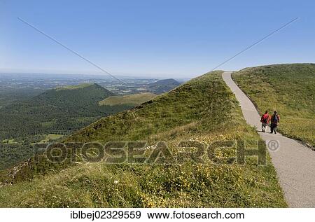 Stock Photo - "Hikers and view from Puy de Dome onto the volcanic landscape of the Chaine des Puys, Auvergne, France, Europe". Fotosearch