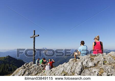 "Hikers at the summit cross of Mt Taubenstein, Mt Bayerischer Schinder and Mt Osterreichischer Schinder at the back, Mangfall mountains, Upper Bavaria, Bavaria, Germany, Europe" View Large Photo Image Stock Photography - "Hikers at the summit cross of Mt Taubenstein, Mt Bayerischer Schinder and Mt Osterreichischer Schinder at the back, Mangfall mountains, Upper Bavaria, Bavaria, Germany, Europe". Fotosearch