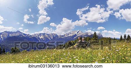 "Hikers sitting on a bench, green meadow on Eckbauer Mountain, Eckbauer, Garmisch-Partenkirchen, Upper Bavaria, Bavaria, Germany, Europe" View Large Photo Image Stock Image - "Hikers sitting on a bench, green meadow on Eckbauer Mountain, Eckbauer, Garmisch-Partenkirchen, Upper Bavaria, Bavaria, Germany, Europe". Fotosearch