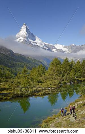 Stock Image - "Hikers taking photographs of the Matterhorn with Lake Grindjisee in the foreground, Zermatt, Canton of Valais, Switzerland, Europe". Fotosearch