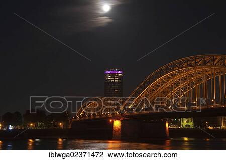 Stock Image - "Hohenzollern Bridge at night, Cologne Triangle tower at back, Rhine, Cologne, Rhineland, North Rhine-Westphalia, Germany, Europe". Fotosearch