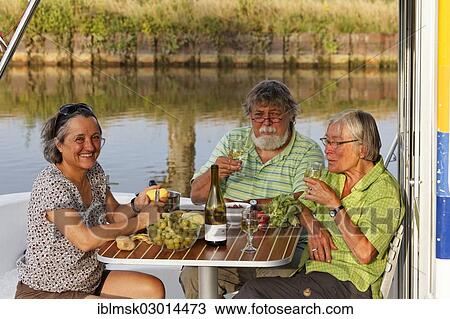 "Holidaymakers enjoying dinner on a houseboat on the Canal des Vosges, formerly Canal de l'Est, Girancourt, Epinal, Lorraine, Departement Vosges, France, Europe" View Large Photo Image Stock Image - "Holidaymakers enjoying dinner on a houseboat on the Canal des Vosges, formerly Canal de l'Est, Girancourt, Epinal, Lorraine, Departement Vosges, France, Europe". Fotosearch