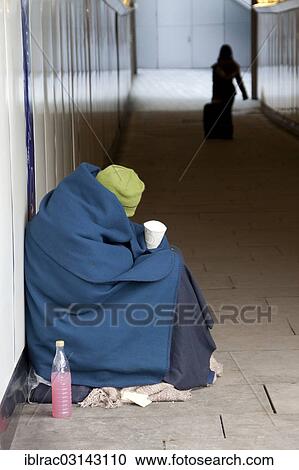 Stock Image - "Homeless person wrapped in a blanket sitting in an underpass, London, London region, England, United Kingdom, Europe". Fotosearch