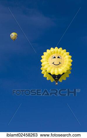 Stock Image - "Hot air balloon in the shape of a """"laughing"""" sun or sunflower against a blue sky, 12th balloon festival of Tegernsee, Montgolfiade, Bad Wiessee, Tegernsee, Bavaria, Germany, Europe". Fotosearch