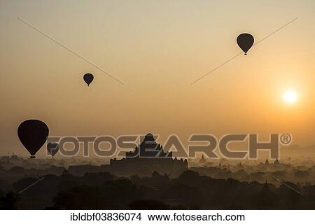 "Hot air balloons over the landscape in the early morning fog, sunrise, Dhammayangyi Temple, stupas, pagodas, temple complex, Plateau of Bagan, Mandalay Division, Burma or Myanmar" View Large Photo Image Picture - "Hot air balloons over the landscape in the early morning fog, sunrise, Dhammayangyi Temple, stupas, pagodas, temple complex, Plateau of Bagan, Mandalay Division, Burma or Myanmar". Fotosearch