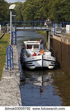 Stock Image - "Houseboat on the Canal des Vosges, formerly Canal de l'Est, entering lock No. 37 to proceed upstream, Ambievillers, Vesoul, Haute-Saone, Franche-Comte, France, Europe". Fotosearch
