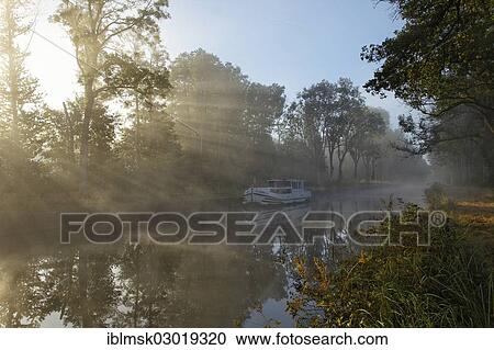 "Houseboat on the Canal des Vosges, formerly Canal de l'Est, overnight stay at PK 100. 5, with morning fog and morning sun, Girancourt, Epinal, Lorraine, Departement Vosges, France, Europe" View Large Photo Image Stock Image - "Houseboat on the Canal des Vosges, formerly Canal de l'Est, overnight stay at PK 100. 5, with morning fog and morning sun, Girancourt, Epinal, Lorraine, Departement Vosges, France, Europe". Fotosearch