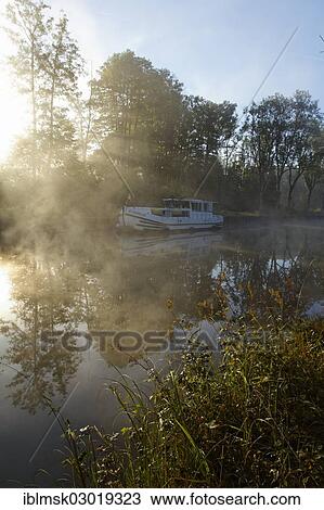 "Houseboat on the Canal des Vosges, formerly Canal de l'Est, overnight stay at PK 100. 5, with morning fog and morning sun, Girancourt, Epinal, Lorraine, Departement Vosges, France, Europe" View Large Photo Image Stock Image - "Houseboat on the Canal des Vosges, formerly Canal de l'Est, overnight stay at PK 100. 5, with morning fog and morning sun, Girancourt, Epinal, Lorraine, Departement Vosges, France, Europe". Fotosearch
