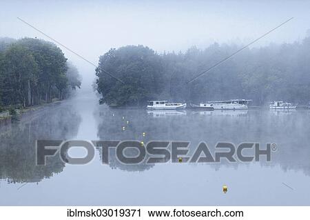 "Houseboats on the Canal des Vosges, formerly Canal de l'Est harbour at Les Forges d'Uzemain, morning mood with morning fog, Uzemain, Epinal, Lorraine, Departement Vosges, France, Europe" View Large Photo Image Stock Image - "Houseboats on the Canal des Vosges, formerly Canal de l'Est harbour at Les Forges d'Uzemain, morning mood with morning fog, Uzemain, Epinal, Lorraine, Departement Vosges, France, Europe". Fotosearch