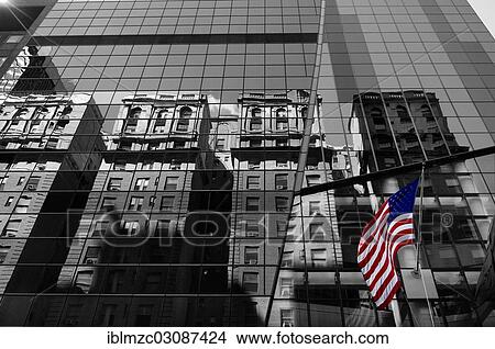 Picture - "Houses are reflected in the glass facade of a skyscraper, with a U. S. flag, New York City, New York, United States, North America". Fotosearch