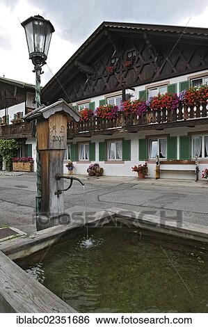 Stock Photograph - "Houses with Geraniums (Pelargonium), balconies and a well, Fruehlingstrasse, Garmisch-Partenkirchen, Bavaria, Germany, Europe". Fotosearch