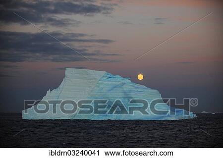 Stock Image - "Iceberg in the open sea with the full moon, Antarctica". Fotosearch