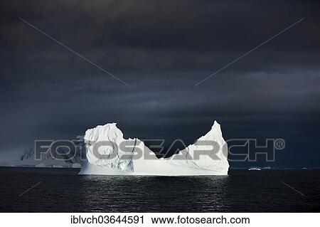 Stock Image - "Iceberg, storm clouds in the morning light, Antarctic Peninsula, Antarctica". Fotosearch