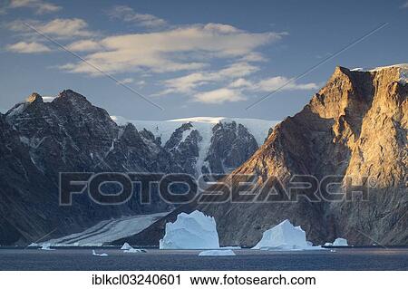 "Icebergs in front of the mountain and glacier scenery in Vest Frederiksdal in the morning light, Nordbugten, Scoresbysund, Sermersooq, Greenland, North America" View Large Photo Image Stock Image - "Icebergs in front of the mountain and glacier scenery in Vest Frederiksdal in the morning light, Nordbugten, Scoresbysund, Sermersooq, Greenland, North America". Fotosearch