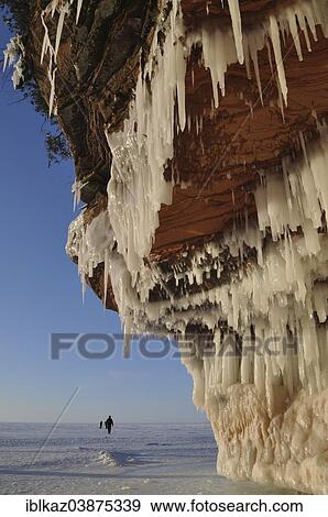 "Icicles hanging from red sandstone cliff and people walking on frozen Lake Superior, Apostle Islands National Lakeshore, Bayfield, Wisconsin, USA" View Large Photo Image Stock Photo - "Icicles hanging from red sandstone cliff and people walking on frozen Lake Superior, Apostle Islands National Lakeshore, Bayfield, Wisconsin, USA". Fotosearch