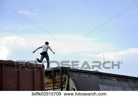 Stock Photo - "Illegal immigrant from Latin America on his way to the U. S. jumping from one waggon to another trying to reach the U. S. border as a stowaway on freight trains, Ixtepec, Oaxaca, Mexico, North America". Fotosearch