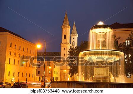 Stock Image - "Illuminated fountain of the University and the Church of St. Louis, Munich, Upper Bavaria, Bavaria, Germany, Europe". Fotosearch