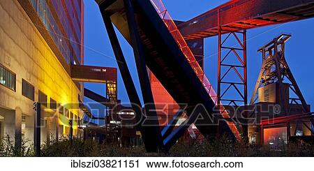 Stock Image - "Illuminated gangway to the Ruhr Museum at the Zeche Zollverein Coal Mine Shaft XII with the headframe, Essen, Ruhr area, North Rhine-Westphalia, Germany, Europe". Fotosearch