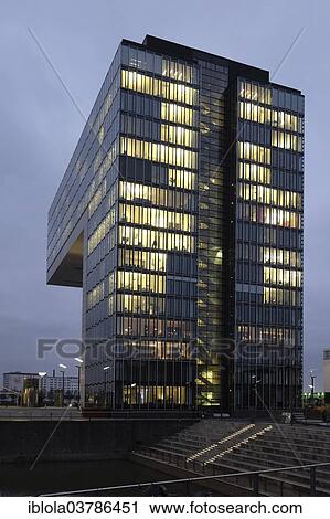 Stock Image - "Illuminated Kranhaus Sud office building at dusk, Rheinauhafen, Cologne, North Rhine-Westphalia, Germany, Europe". Fotosearch