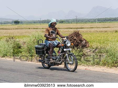 Stock Image - "Indian man driving a motorcycle, Uttamapalaiyam, Tamil Nadu, India, Asia". Fotosearch