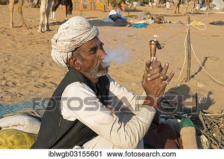 "Indian with a turban sitting on the ground smoking a hash pipe, Pushkar Camel Fair, Pushkar, Rajasthan, India, Asia" View Large Photo Image Stock Image - "Indian with a turban sitting on the ground smoking a hash pipe, Pushkar Camel Fair, Pushkar, Rajasthan, India, Asia". Fotosearch
