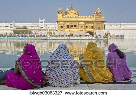 Stock Photo - "Indian women, pilgrims wearing colorful saris sitting on the edge of the water basin of the Amrit Sagar, or Holy Lake, Harmandir Sahib or Hari Mandir or Golden Temple, the most important Sikh temple, Amritsar, Punjab, India, Asia". Fotosearch