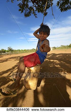 "Indigenous boy playing on a makeshift swing under a tree, village of the Xavantes pople, Tres Rios near the mission of Sangradouro, Primavera do Leste, Mato Grosso, Brazil, South America" View Large Photo Image Stock Photograph - "Indigenous boy playing on a makeshift swing under a tree, village of the Xavantes pople, Tres Rios near the mission of Sangradouro, Primavera do Leste, Mato Grosso, Brazil, South America". Fotosearch