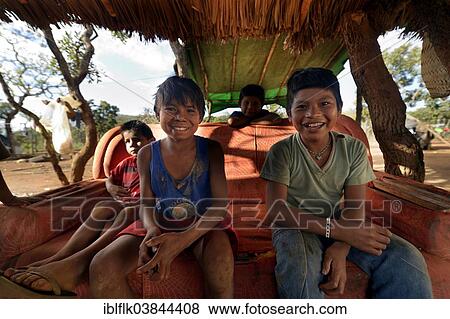 "Indigenous children sitting on an old sofa in the shade, in the village of the Xavantes people, Tres Rios near the mission of Sangradouro, Primavera do Leste, Mato Grosso, Brazil, South America" View Large Photo Image Stock Photo - "Indigenous children sitting on an old sofa in the shade, in the village of the Xavantes people, Tres Rios near the mission of Sangradouro, Primavera do Leste, Mato Grosso, Brazil, South America". Fotosearch