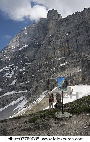 Stock Photo - "Info panel and hikers on the Eiger Trail, behind the Eiger North Face, Swiss Alps Jungfrau-Aletsch UNESCO World Heritage, Grindelwald, Canton of Bern, Switzerland, Europe". Fotosearch